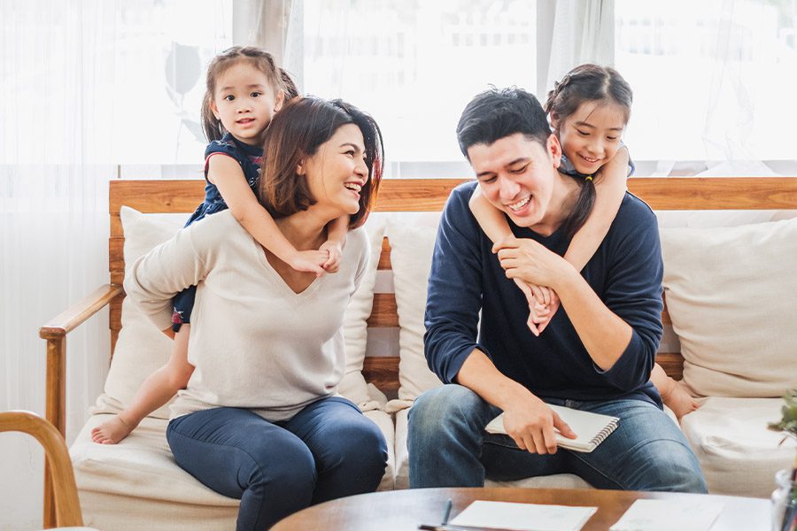Personal Insurance - Happy Family Playing Together on the Sofa in Their Living Room